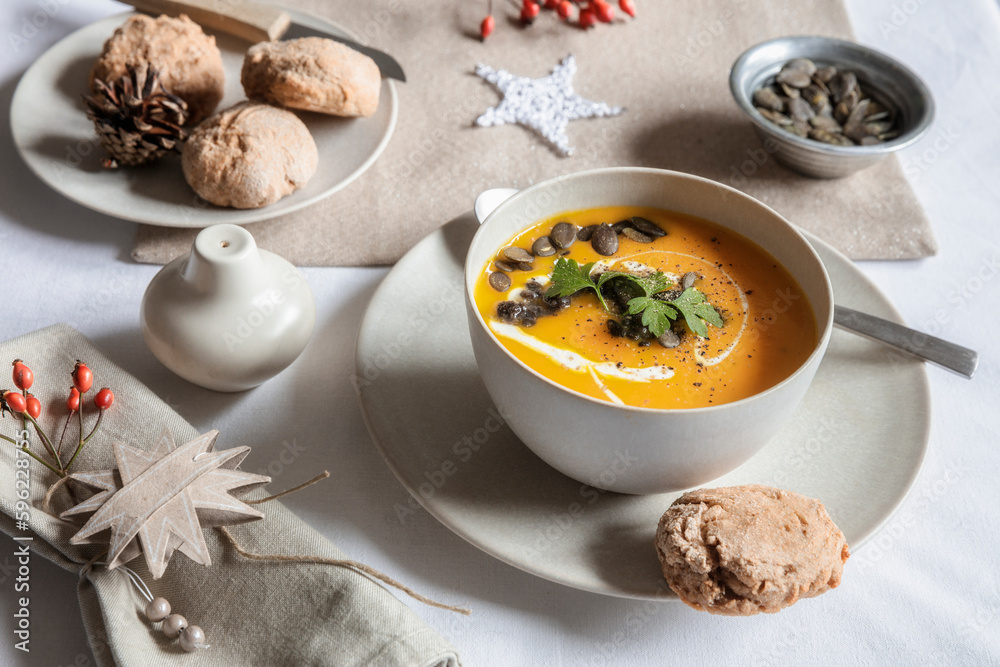 Studio shot of bowl of pumpkin soup with homemade buns in Christmas setting Studio shot of bowl of pumpkin soup with homemade buns in Christmas setting