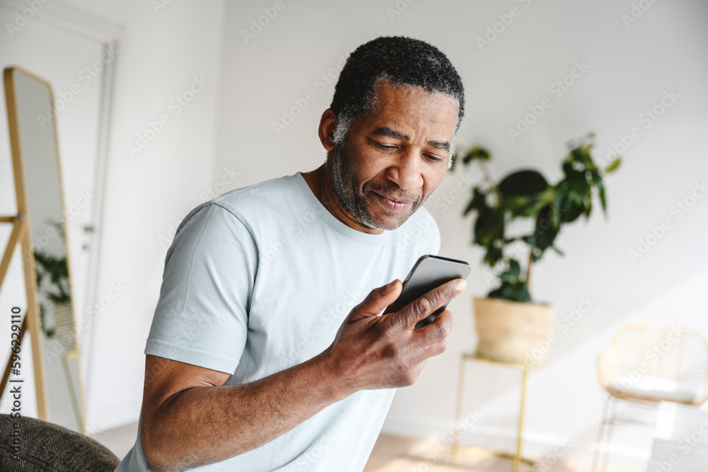 © Westend61 - Mature man using mobile phone at home