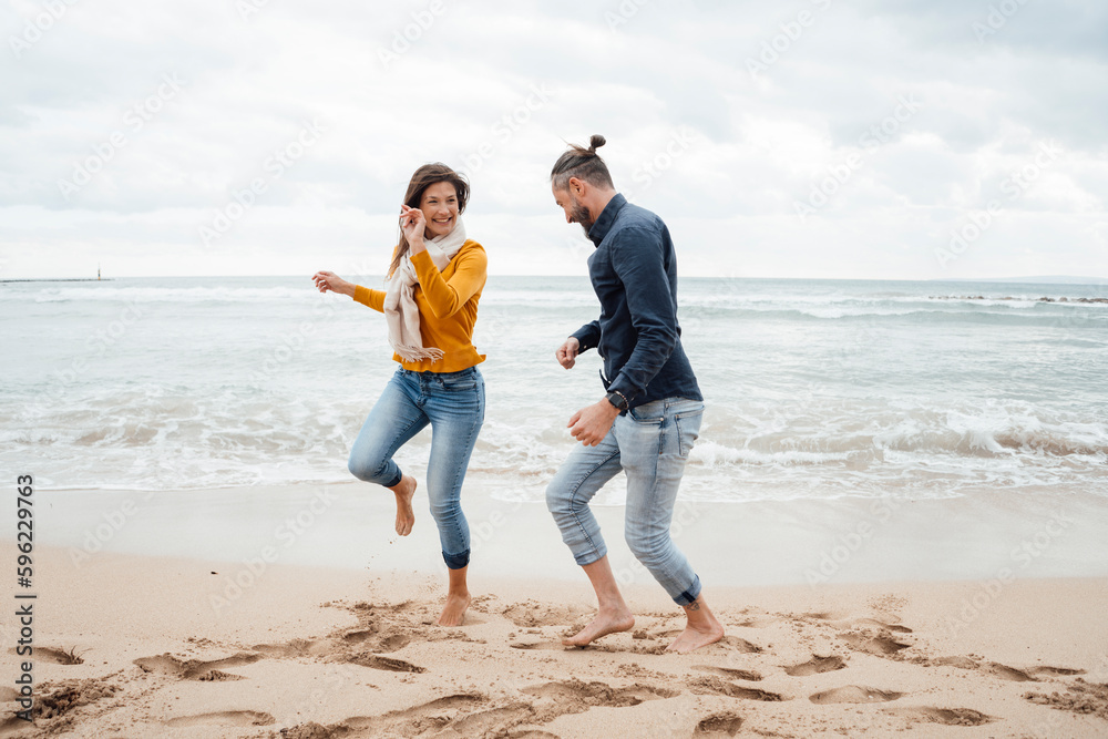 Cheerful couple dancing in front of sea at beach Cheerful couple dancing in front of sea at beach