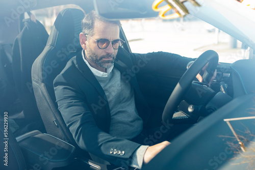 Businessman sitting in electric car seen through windshield photo