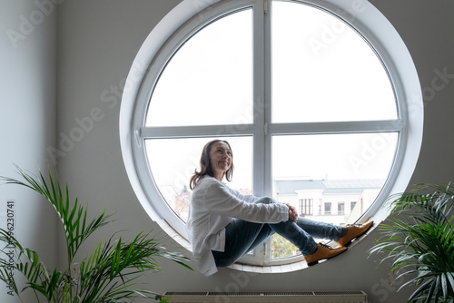Thoughtful businesswoman sitting on round shape window sill