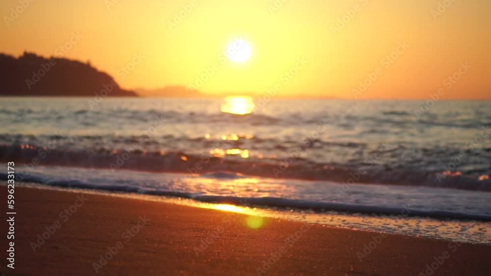 Golden sunset on the beach. Foamy waves rolling towards golden sand beach under low warm sun light. Slow motion. Nobody. Holiday recreation concept. Abstract nautical summer ocean sunset nature. Golden sunset on the beach. Foamy waves rolling towards golden sand beach under low warm sun light. Slow motion. Nobody. Holiday recreation concept. Abstract nautical summer ocean sunset nature.