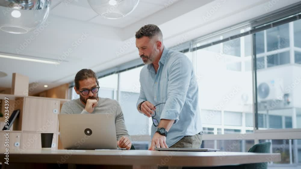 Two software developers discussing a project in an office, using a laptop to review their progress. Innovative business men collaborating on a tech solution using their expertise in the field.