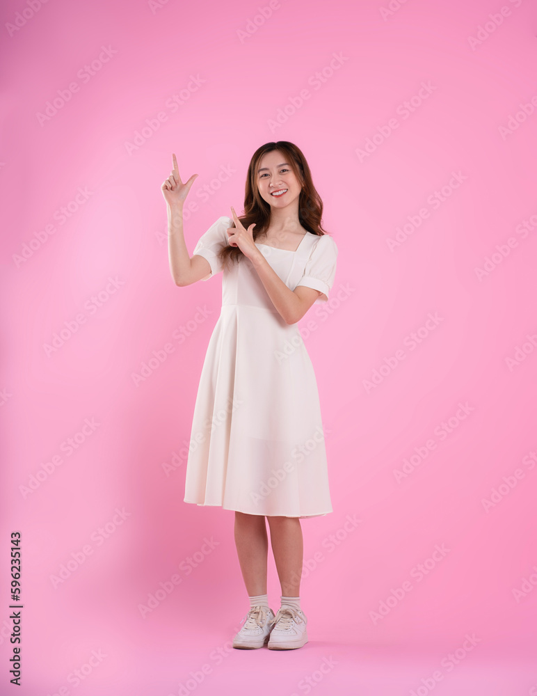 full body image of asian woman in skirt posing on pink background