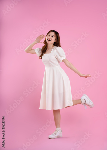 full body image of asian woman in skirt posing on pink background