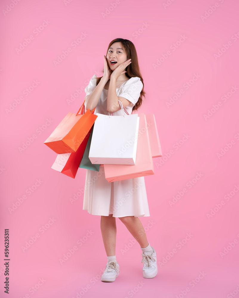full body image of asian woman holding shopping bag and posing on pink background full body image of asian woman holding shopping bag and posing on pink background