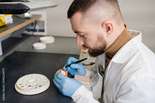 Fotografie Dental technician using a brush with ceramic dental implants in his laboratory