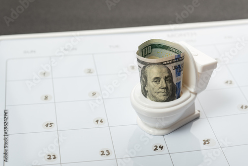 фотографія Toy white toilet bowl with cash dollars on calendar background