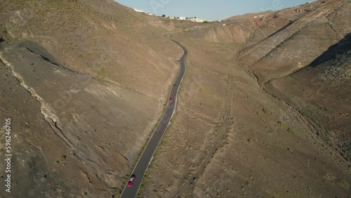 Los Ajaches winding road surrounded by rocky mountains with several cars moving along it   photo