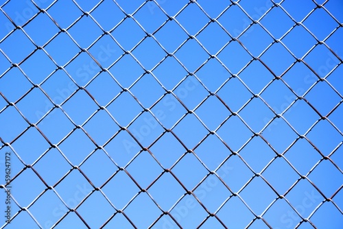 Part of a soccer field fence with a view of the blue clear sky