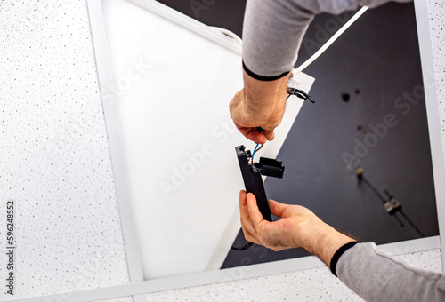 Close-up of a male electrician installing a ceiling lamp repairing and connecting cables