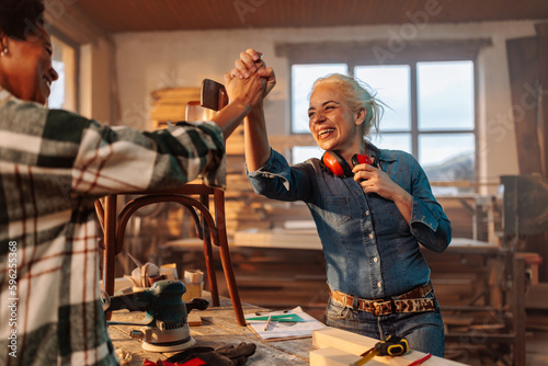 Foto Happy multiethnic coworkers high five in wood workshop.
