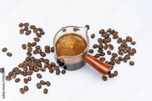 Shot coffee in a measuring cup on a white background with coffee beans