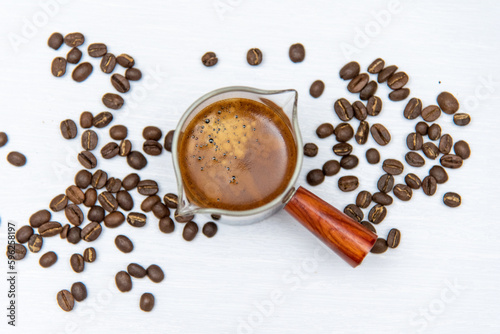Shot coffee in a measuring cup on a white background with coffee beans