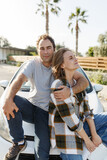Happy cheerful young people couple enjoy the travel and active lifestyle, caucasian man and woman taking break on trip road together standing next to rented car outdoor. Travel, adventure concept. 