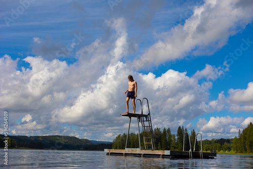 Boy climbing diving platform on lake photo