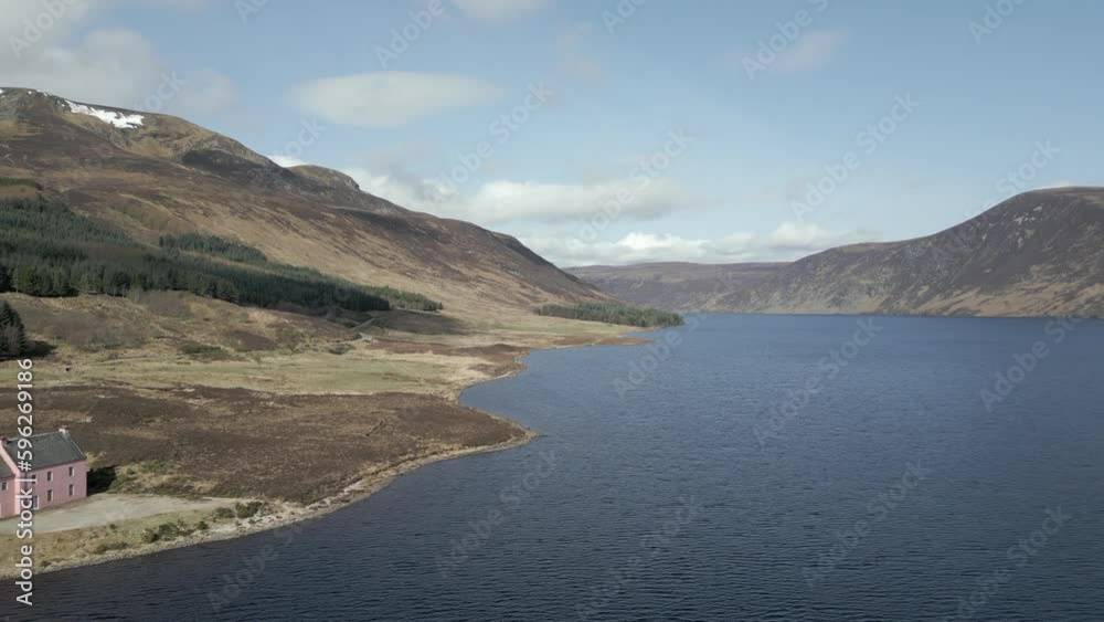 Aerial view of the famous Pink House on the shores of Loch Glass in the Scottish Highlands on a sunny spring day. Drone view flying right to left with the Pink House moving left to right across frame. Aerial view of the famous Pink House on the shores of Loch Glass in the Scottish Highlands on a sunny spring day. Drone view flying right to left with the Pink House moving left to right across frame.