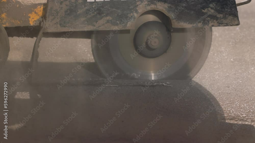 Pothole repair on a road. Close-up of a circular saw cutting out a section of the old asphalt to be replaced with new material. Pothole repair on a road. Close-up of a circular saw cutting out a section of the old asphalt to be replaced with new material.