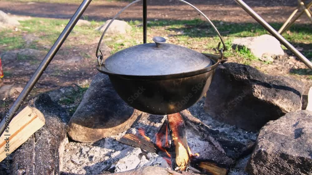 Cauldron is over campfire cooks food for travelers. Stone fireplace in the forest. High quality 4k footage Cauldron is over campfire cooks food for travelers. Stone fireplace in the forest. High quality 4k footage