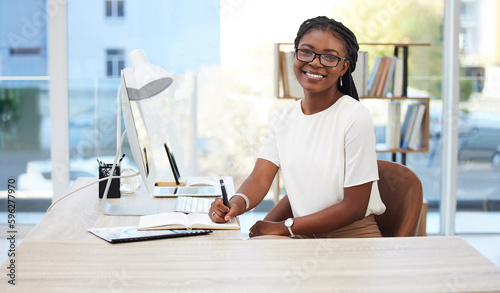 Planning assures everything goes smoothly. Shot of a young businesswoman writing in a notebook at work. photo