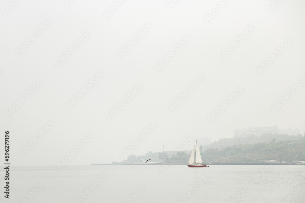 Landscape of a foggy sea with a sailboat on the horizon