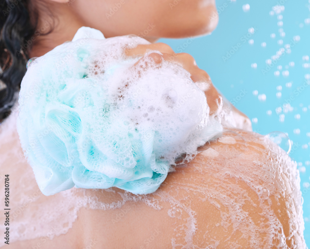 Fototapeta premium Use a loofah for a deeper clean. Studio shot of an unrecognizable young woman showering against a blue background.