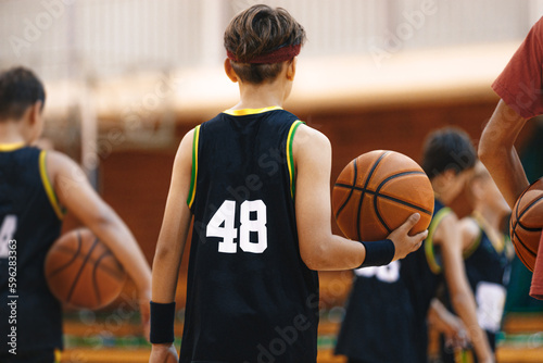 Youth basketball team on training. Basketball training session for school kids. Young basketball player with classic ball. Junior level basketball player holding game ball © matimix