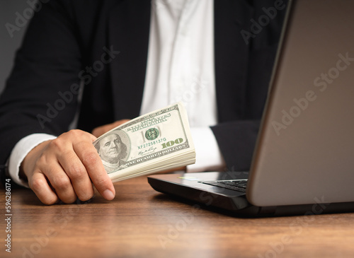 Personal loan concept. Businessman in a suit holding US dollar bills while sitting in the office