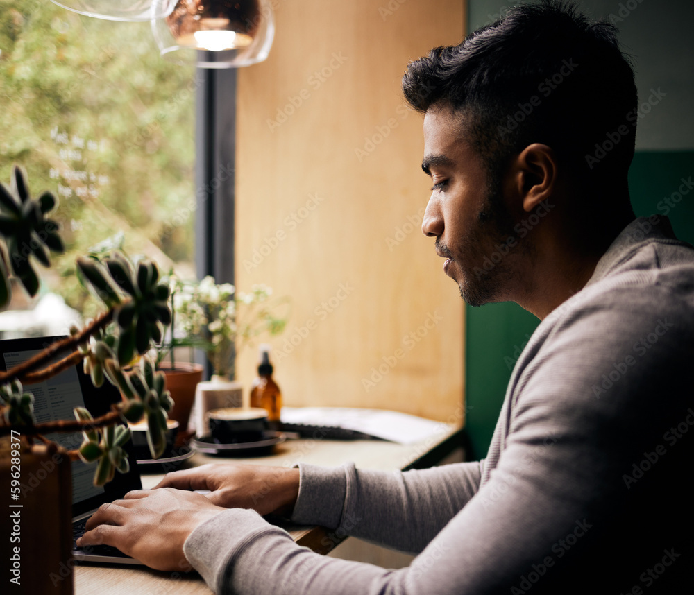 Young mixed race man or student browsing on a laptop in a cafe. One indian guy studying or working freelance at a restaurant. Typing to do research and planning online for blog, work or assignment Young mixed race man or student browsing on a laptop in a cafe. One indian guy studying or working freelance at a restaurant. Typing to do research and planning online for blog, work or assignment
