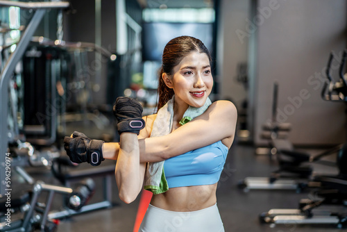 Active young Asian woman stretching her body warm up before intensive workout at gym, basic gym exercises performed by the young female