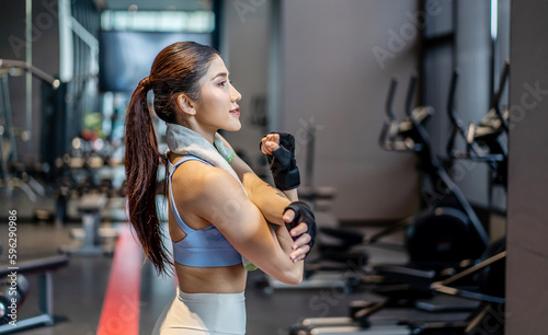 Active young Asian woman stretching her body warm up before intense workout at gym  basic gym exercises performed by the young female