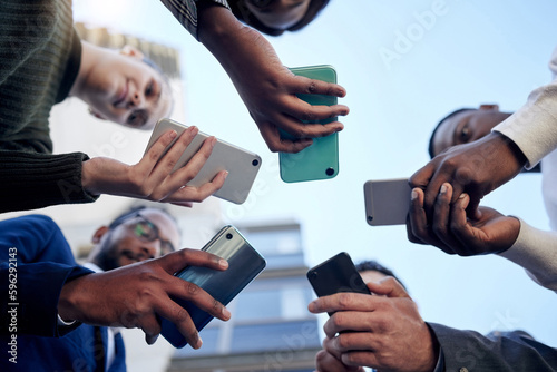 Sharing important news. Shot of a group of businesspeople using phones outside.