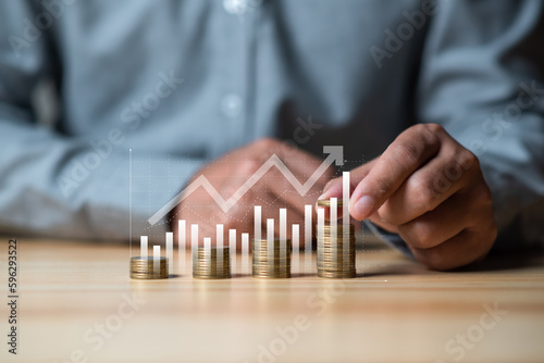 Investment and financial concept, businessman 's hand with money coin stacking and push arrow up to make a financial growth and profit , deposit and saving concept.