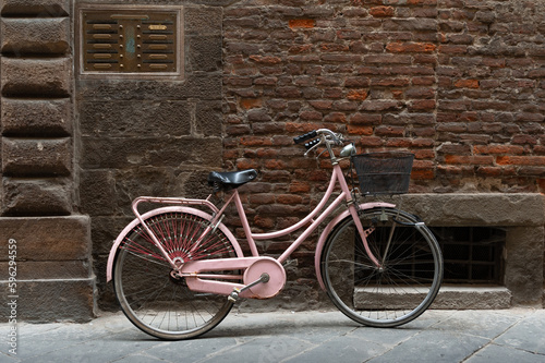 Una bicicleta aparcada contra un muro de ladrillo en una calle de Lucca, Italia.