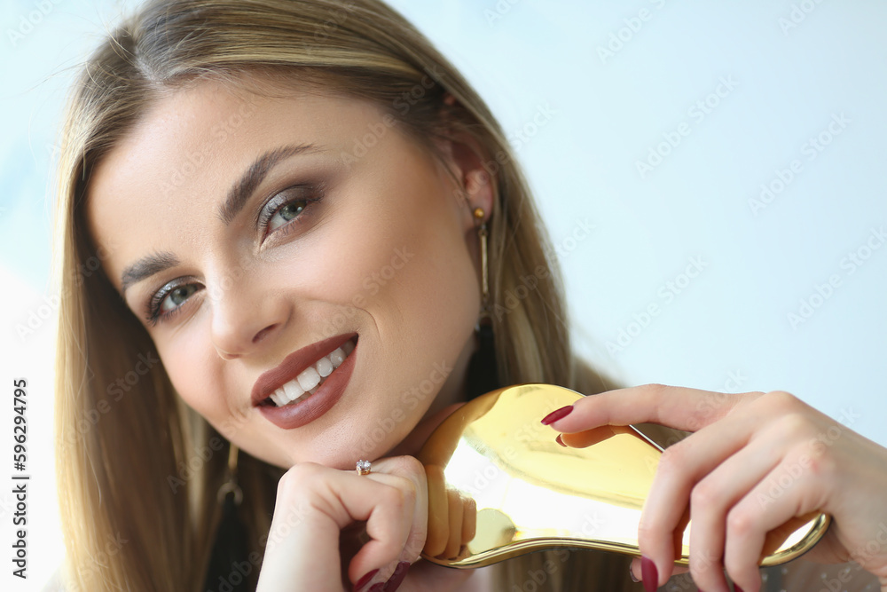 Beautiful blonde smiles and combs long hair. Women hair care and beauty and health concept Beautiful blonde smiles and combs long hair. Women hair care and beauty and health concept