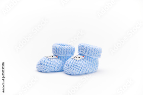 A pair of handmade blue knitted baby booties, isolated on white background. Newborn clothing and pregnancy concept. Copy space for advertising text. Fashion.