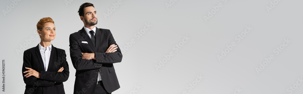 happy redhead businesswoman and confident businessman looking away isolated on grey, banner.