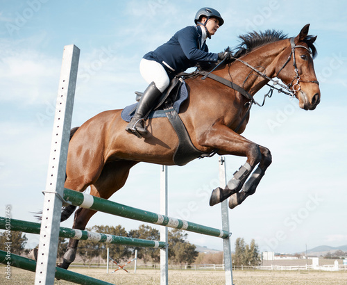 Hurdling obstacles with ease. Full length shot of a young female rider jumping over a hurdle on her horse.