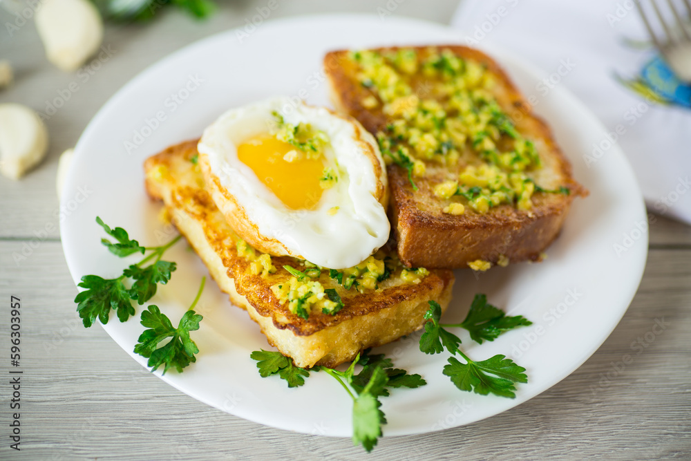 Fried croutons in batter with garlic and herbs and a fried egg in a plate. Fried croutons in batter with garlic and herbs and a fried egg in a plate.
