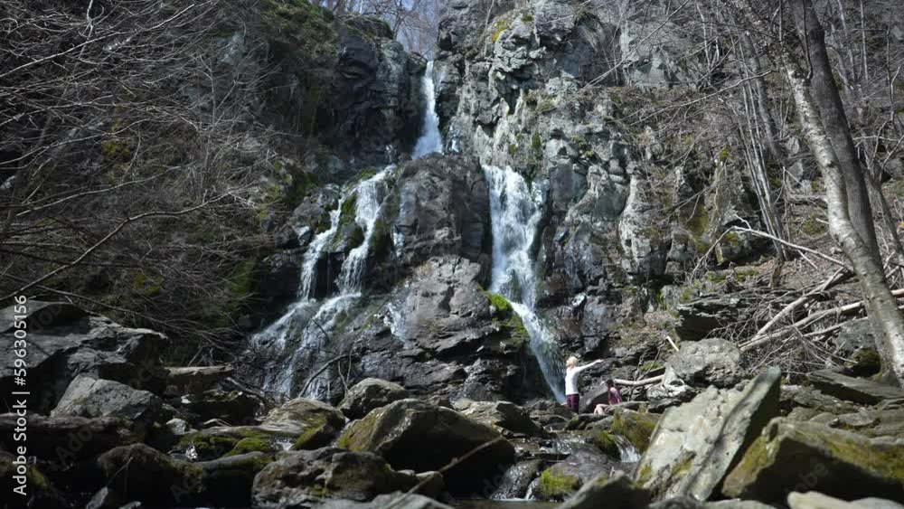 Mature woman with arms outstretched feeling freedom, success hiking with dog to waterfall in Shenandoah National Park in Blue Ridge mountains of Virginia. 