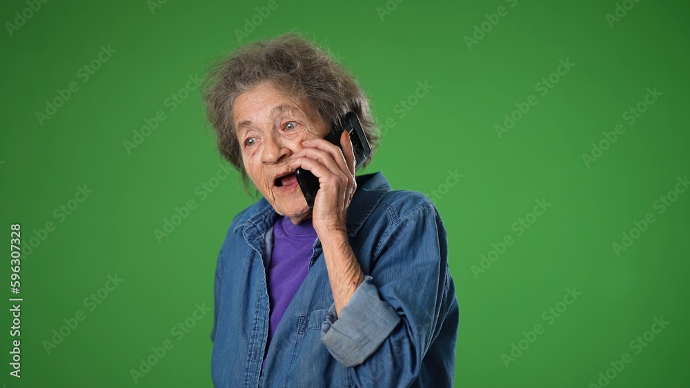 Funny crazy elderly old toothless woman answering call and talking on phone isolated on green screen background with mock up copy space. Funny crazy elderly old toothless woman answering call and talking on phone isolated on green screen background with mock up copy space.