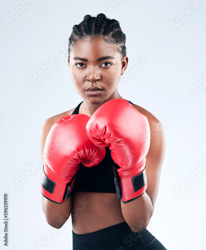 Im fighting back. Studio shot of a sporty young woman wearing boxing gloves while posing against a studio background. © Jade M/peopleimages.com