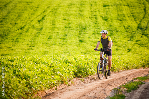 Young cyclist cycling in the spring meadow