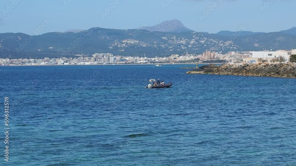 a small sports boat sails slowly entering the nautical club of Cala Gamba in Mallorca
