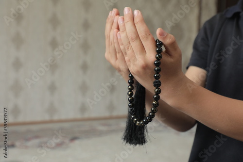 A person is holding a prayer beads on their hands.