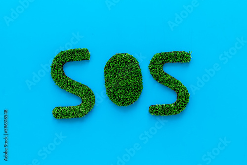 Word SOS made of green grass. Save the Earth planet ecology concept.