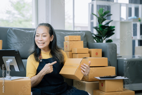Startup small business entrepreneur or freelance using a laptop with box, checking orders from customers, matron runs an e-commerce business on websites and social media.