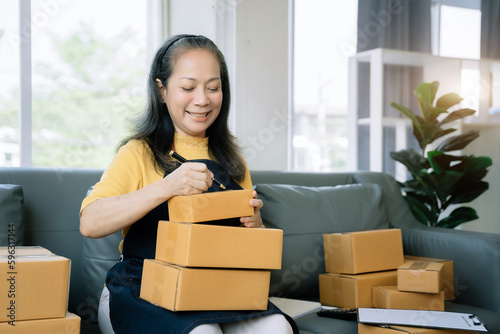 Startup small business entrepreneur or freelance using a laptop with box, checking orders from customers, matron runs an e-commerce business on websites and social media. 