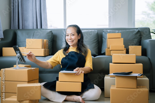 Startup small business entrepreneur or freelance using a laptop with box, checking orders from customers, matron runs an e-commerce business on websites and social media. 
