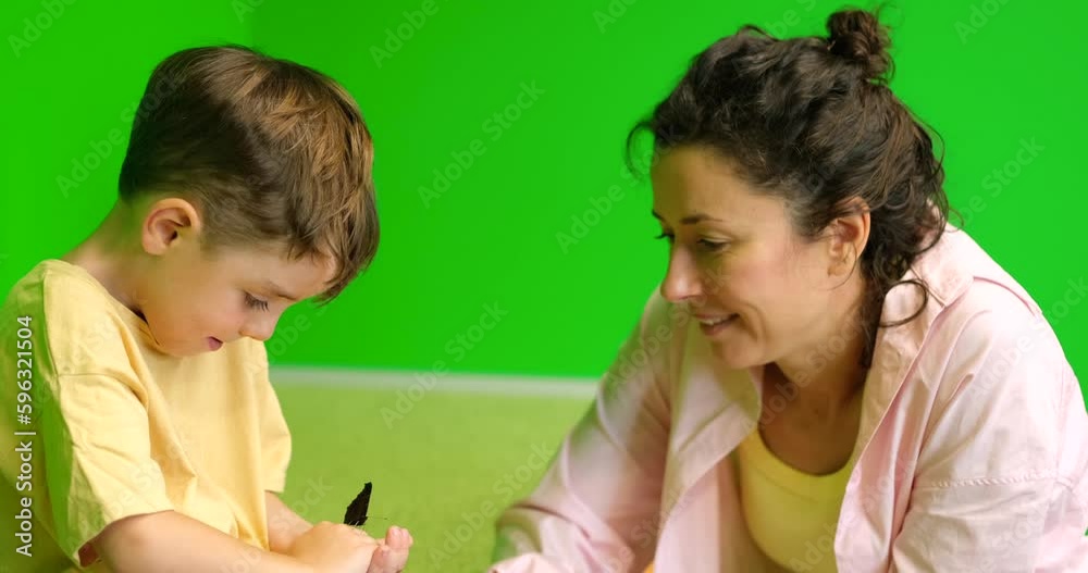 Alive butterfly: mom and small kid enjoying nature at home looking together at beautiful butterfly in child hands. Loving parent female enjoy spending time with boy on weekend. High quality 4k video